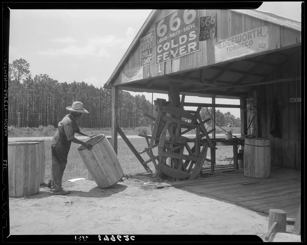 Turpentine still near Valdosta, Georgia. The "cooper" makes barrels…, 1937