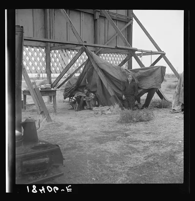 One of three families camped behind a billboard on U.S. 99. Kern…, California, 1938