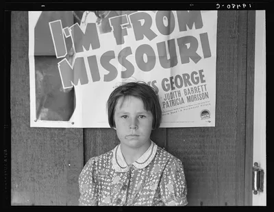 Advertisement for current movie in town. The child is a flood refugee…, California, 1939